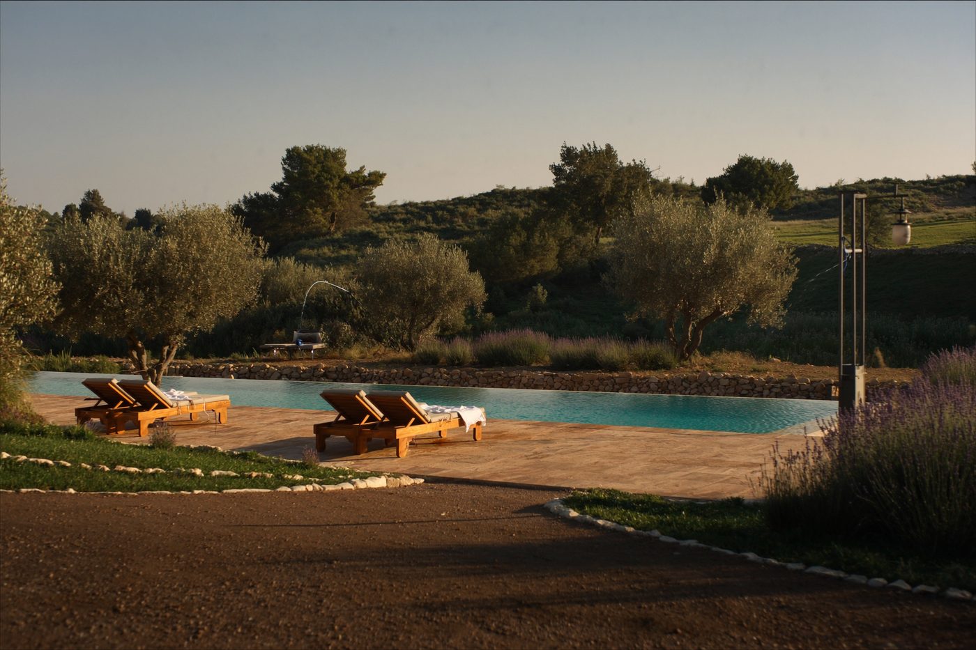 Private Mediterranean villa pool at golden hour, surrounded by olive trees and lavender